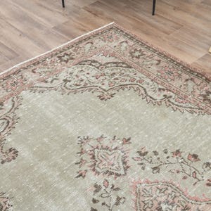 Puede incluir: Una alfombra vintage con fondo verde claro y un patr&oacute;n floral rosa y marr&oacute;n. La alfombra tiene un aspecto desgastado y es perfecta para a&ntilde;adir un toque de estilo bohemio a tu hogar.