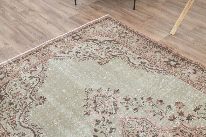 Puede incluir: Una alfombra vintage con fondo verde claro y un patr&oacute;n floral rosa y marr&oacute;n. La alfombra tiene un aspecto desgastado y es perfecta para a&ntilde;adir un toque de estilo bohemio a tu hogar.