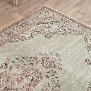 Puede incluir: Una alfombra vintage con fondo gris claro y un patr&oacute;n floral rosa y marr&oacute;n. La alfombra tiene un aspecto desgastado y es perfecta para a&ntilde;adir un toque de estilo bohemio a tu hogar.