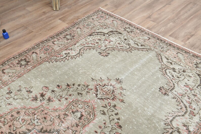 Puede incluir: Una alfombra vintage con fondo gris claro y un patr&oacute;n floral rosa y marr&oacute;n. La alfombra tiene un aspecto desgastado y es perfecta para a&ntilde;adir un toque de estilo bohemio a tu hogar.