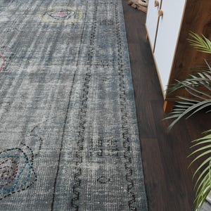 May include: A gray and white patterned rug with a distressed look. The rug has a border of dark blue and white.