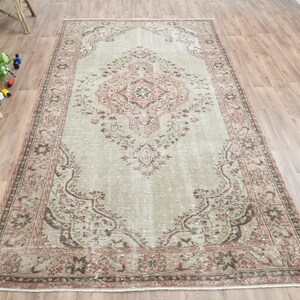 Puede incluir: Una alfombra vintage con fondo verde claro y un patr&oacute;n floral rosa y marr&oacute;n. La alfombra tiene un aspecto desgastado y es perfecta para a&ntilde;adir un toque de estilo bohemio a cualquier habitaci&oacute;n.