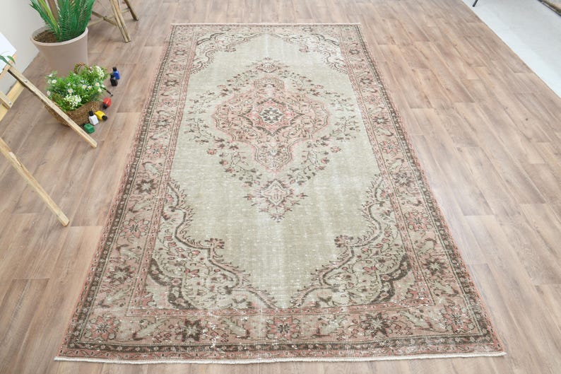Puede incluir: Una alfombra vintage con fondo verde claro y un patr&oacute;n floral rosa y marr&oacute;n. La alfombra tiene un aspecto desgastado y es perfecta para a&ntilde;adir un toque de estilo bohemio a cualquier habitaci&oacute;n.