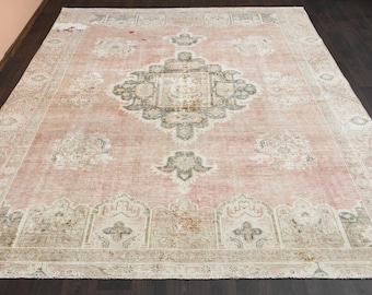May include: A vintage rug with a faded pink background and a central medallion design in beige and grey. The rug has a distressed look with a worn and faded appearance.