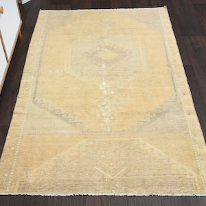 Puede incluir: Una alfombra beige claro con un patrón geométrico descolorido. La alfombra tiene un aspecto desgastado y está hecha de fibras naturales.