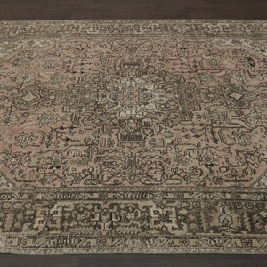 May include: A large, rectangular rug with a detailed, faded floral pattern in pink, brown, and cream. The rug features a complex border and a central medallion design, giving it a vintage appearance. Suitable for a living room or bedroom.