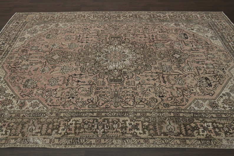May include: A large, rectangular rug with a detailed, faded floral pattern in pink, brown, and cream. The rug features a complex border and a central medallion design, giving it a vintage appearance. Suitable for a living room or bedroom.