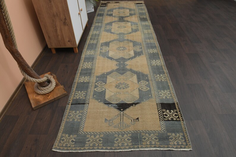 May include: A vintage style runner rug with a blue and beige colour scheme. The rug has a geometric pattern with a central medallion.