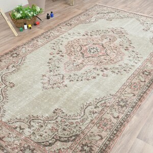 Puede incluir: Una alfombra vintage con un patr&oacute;n floral descolorido en tonos rosa, marr&oacute;n y crema. La alfombra tiene un aspecto desgastado y es perfecta para a&ntilde;adir un toque de estilo bohemio a cualquier habitaci&oacute;n.