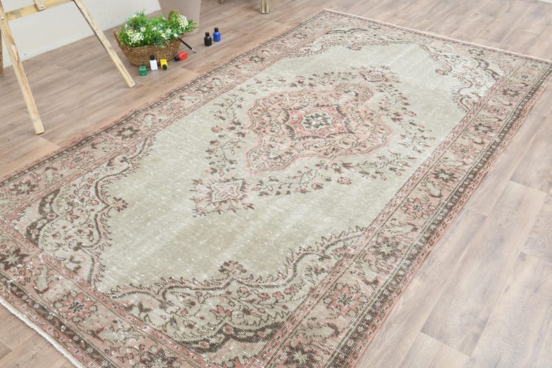 Puede incluir: Una alfombra vintage con un patr&oacute;n floral descolorido en tonos rosa, marr&oacute;n y crema. La alfombra tiene un aspecto desgastado y es perfecta para a&ntilde;adir un toque de estilo bohemio a cualquier habitaci&oacute;n.