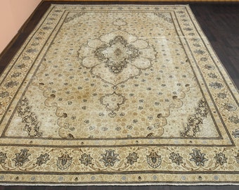 Puede incluir: Una alfombra beige con un patrón floral y un medallón central. La alfombra tiene un borde marrón con un diseño floral.