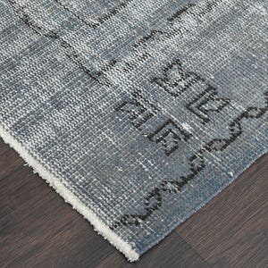 May include: Close-up of the edge of a blue and white patterned rug with a white fringe. The rug has a geometric design with black accents.