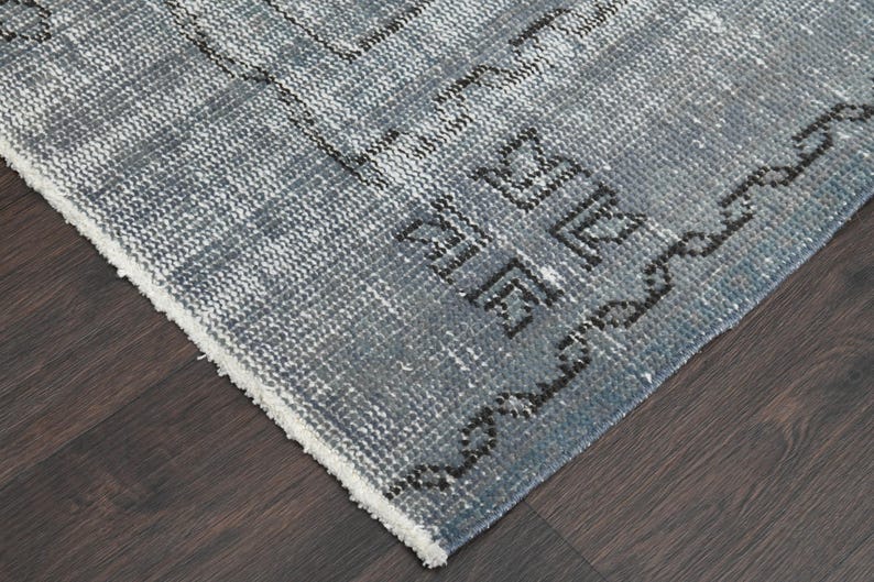 May include: Close-up of the edge of a blue and white patterned rug with a white fringe. The rug has a geometric design with black accents.
