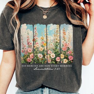 May include: A dark grey t-shirt with a floral print and the text "HIS MERCIES ARE NEW EVERY MORNING Lamentations 3:23".