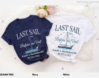 May include: Two t-shirts, one navy and one white, with the text "LAST SAIL Before the Veil" and a sailboat graphic. The text "Emily's Bachelorette PUNTA CANA" is also printed on the shirts. The shirts are made by Gildan Tees.