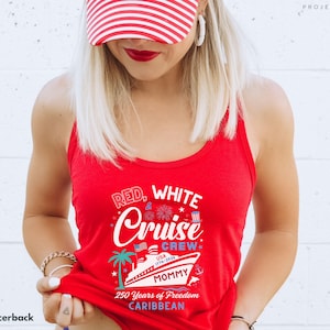 Puede incluir: Una camiseta sin mangas roja con el texto "RED, WHITE & Cruise Crew" y un gr&aacute;fico de un crucero, una palmera y fuegos artificiales. Tambi&eacute;n se muestra el texto "USA 1776-2026" y "250 Years of Freedom Caribbean". La camiseta sin mangas es roja.