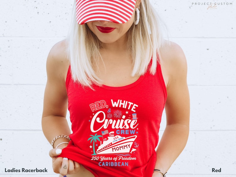 Puede incluir: Una camiseta sin mangas roja con el texto "RED, WHITE & Cruise Crew" y un gr&aacute;fico de un crucero, una palmera y fuegos artificiales. Tambi&eacute;n se muestra el texto "USA 1776-2026" y "250 Years of Freedom Caribbean". La camiseta sin mangas es roja.