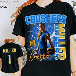 May include: Black t-shirt featuring a volleyball player graphic. The design includes the text "CRUSHERS MILLER" in blue and yellow, with the name "Chesica" in a script font. The back of the shirt displays "MILLER" and the number "1".