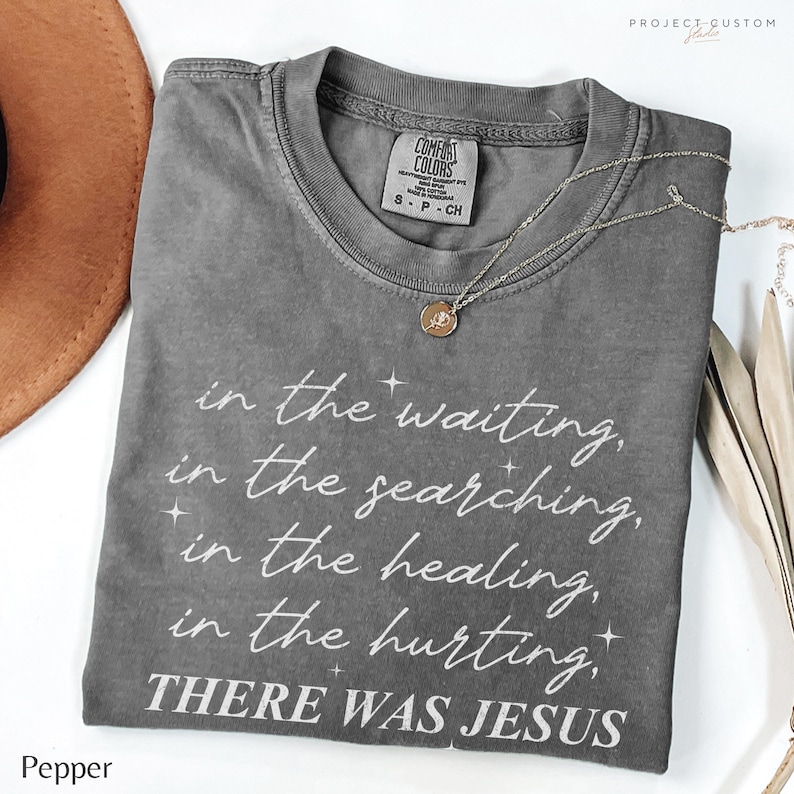 Pu&ograve; includere: Maglietta grigia con una grafica bianca che recita "in the waiting, in the searching, in the healing, in the hurting, THERE WAS JESUS".