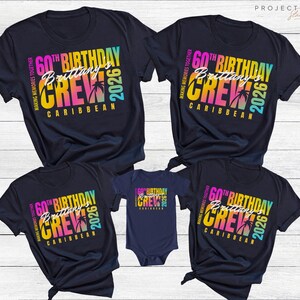 May include: Navy blue t-shirts and a onesie with a colorful graphic. The design includes the text "60th Birthday Crew Brittany Caribbean 2026" with palm trees. The shirts are for a family or group.