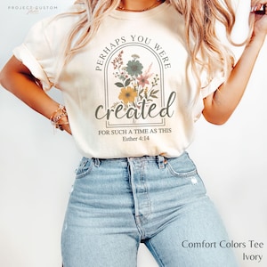 May include: A white t-shirt with a floral design and the text "Perhaps you were created for such a time as this Esther 4:14".