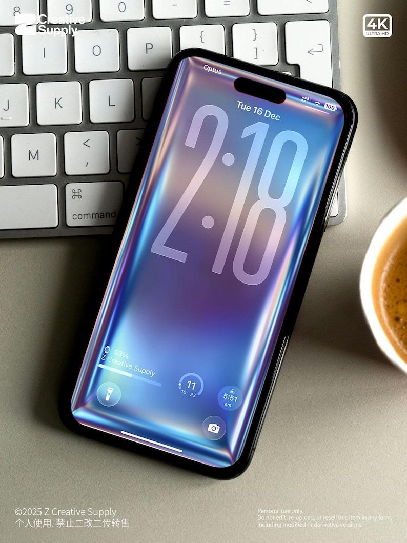 May include: A smartphone with a black frame displays the time 2:18 on a blue and purple gradient background. The screen shows the date, battery life, and other icons. The phone rests on a keyboard.
