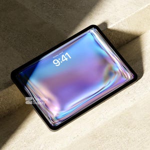 May include: A tablet with a black frame displaying a vibrant, iridescent liquid-like wallpaper in shades of blue, purple, and pink. The screen shows the time 9:41 and the date Monday, June 9. The text Creative Supply is visible on the screen.