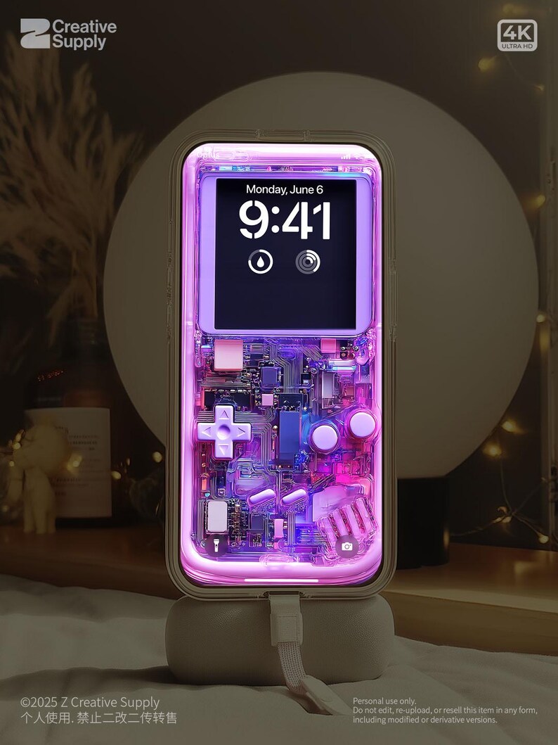 May include: A transparent phone case with a retro video game design, lit with purple and pink lights. The phone screen shows the time, "Monday, June 6, 9:41." The case features a cross-shaped directional pad and other game controller elements. The text "Creative Supply" is visible.