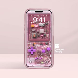 May include: A pink phone case with a retro video game design. The case has a D-pad, buttons, and internal circuitry visible through the transparent material. The phone screen shows the time and date. The Creative Supply logo is visible.
