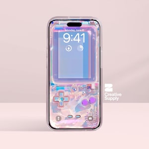 Puede incluir: Funda transparente para teléfono con diseño de videojuego retro. La funda presenta una cruceta direccional, botones morados y una pantalla que muestra la hora y la fecha. El logotipo de Creative Supply es visible.