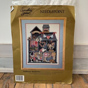 May include: Needlepoint pattern for a dollhouse shadowbox. The design features a multi-level dollhouse with a red, white, and blue color scheme. The text "Something Special" is printed in the top left corner. The text "Needlepoint" is printed in the top right corner. The text "Dollhouse Shadowbox" is printed in the bottom center. The text "MCMXC CANDIDAM DESIGNS INC." is printed in the bottom right corner.
