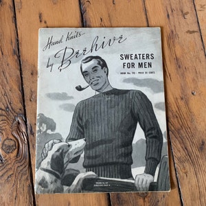 May include: A vintage knitting pattern booklet cover featuring a man wearing a striped sweater and holding a dog. The cover is titled "Hand Knits by Beehive" and "Sweaters for Men". The text also includes "Book No. 110 - Price 25 Cents".