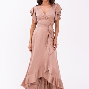 May include: A long, flowing, mauve wrap dress with a V-neckline and ruffled sleeves. The dress has a tie at the waist and a ruffled hem.