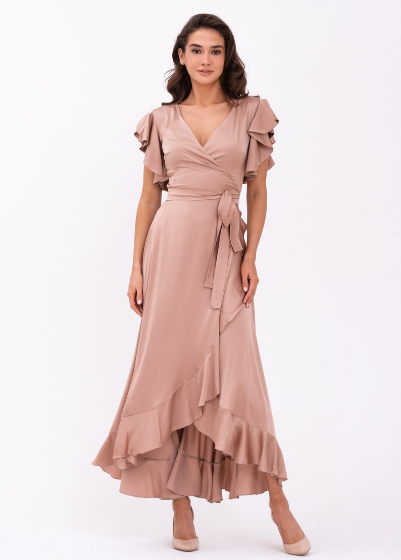 May include: A long, flowing, mauve wrap dress with a V-neckline and ruffled sleeves. The dress has a tie at the waist and a ruffled hem.