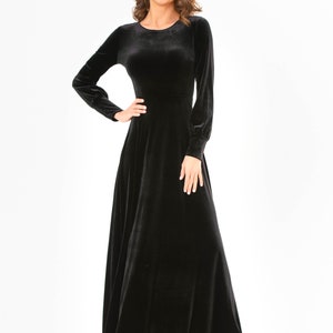 May include: A long-sleeved black velvet maxi dress with a round neckline. The dress has a fitted bodice and a flowing skirt.