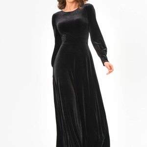 May include: A long-sleeved black velvet dress with a round neckline and a flowing skirt.