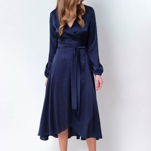 May include: A navy blue satin wrap dress with long sleeves and a tie at the waist. The dress has a high neckline and a high-low hemline.