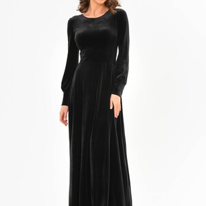 May include: A long-sleeved black velvet dress with a round neckline and a flowing skirt.