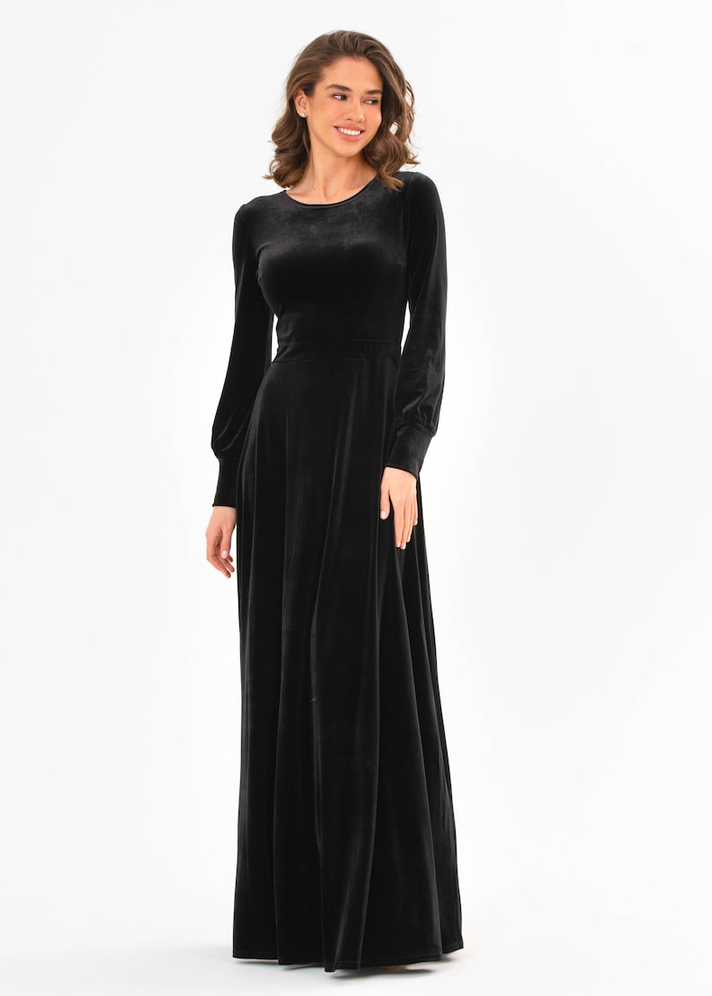 May include: A long-sleeved black velvet dress with a round neckline and a flowing skirt.
