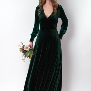 K&ouml;nnte beinhalten: Ein lang&auml;rmeliges, smaragdgr&uuml;nes Samtkleid mit V-Ausschnitt und Wickel-Oberteil. Das Kleid hat einen flie&szlig;enden Rock und ist perfekt f&uuml;r einen formellen Anlass.