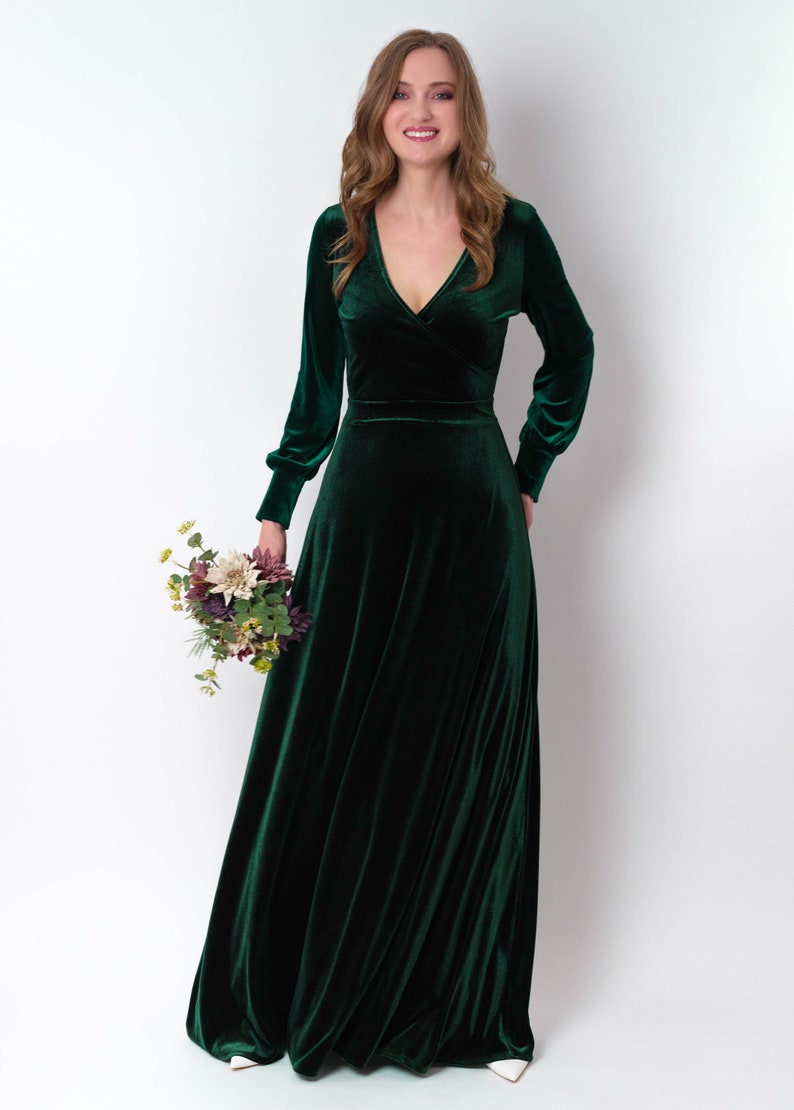 K&ouml;nnte beinhalten: Ein lang&auml;rmeliges, smaragdgr&uuml;nes Samtkleid mit V-Ausschnitt und Wickel-Oberteil. Das Kleid hat einen flie&szlig;enden Rock und ist perfekt f&uuml;r einen formellen Anlass.