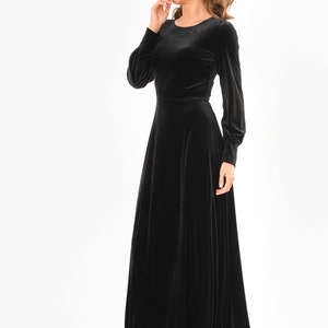 May include: A black velvet maxi dress with long sleeves and a round neckline.