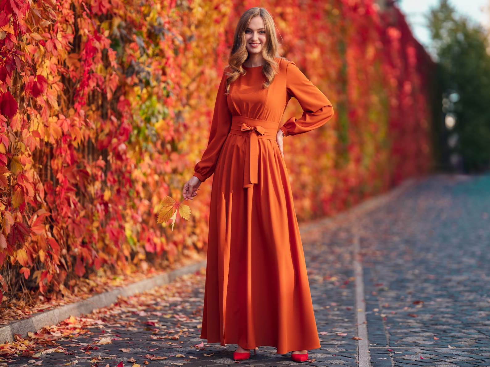 Woman wearing a rust-orange midi dress with a shawl as a fall wedding guest