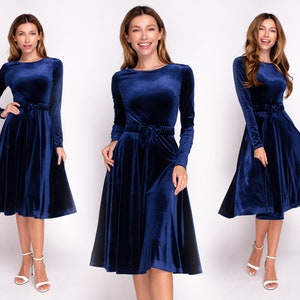 May include: A navy blue velvet dress with long sleeves and a fitted bodice. The dress has a flared skirt and a tie at the waist.
