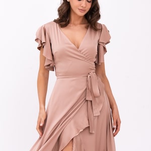 May include: A long, flowing, blush-coloured wrap dress with a V-neckline, ruffled sleeves, and a tie at the waist.