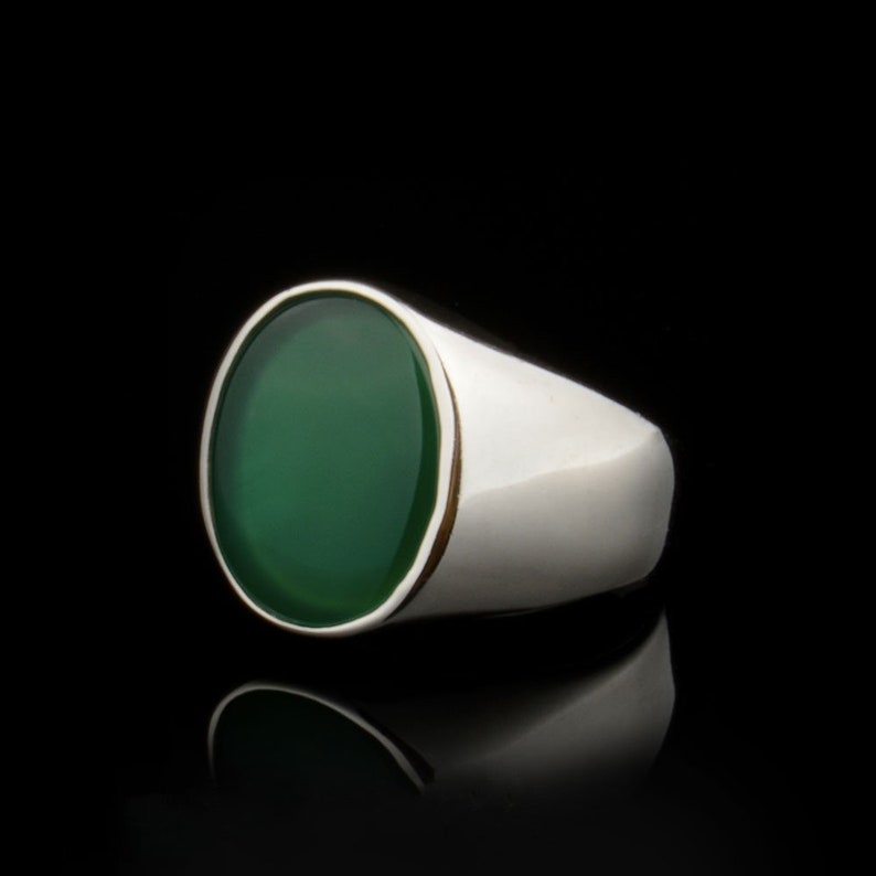 Puede incluir: Un anillo de plata con una gran piedra preciosa verde de forma ovalada.