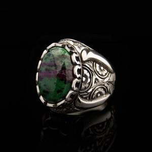 May include: A silver ring with an oval green and pink gemstone set in a detailed floral design.
