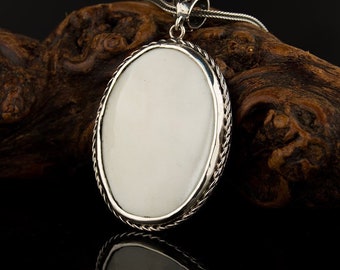 May include: A silver pendant with a white oval-shaped stone set in a rope-like border. The pendant is hanging from a silver chain.