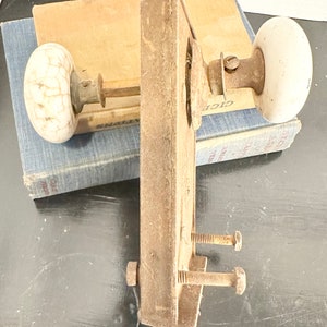 May include: A vintage door hardware set with two white porcelain door knobs and a rusty metal door plate. The door plate has two screws and a metal latch.