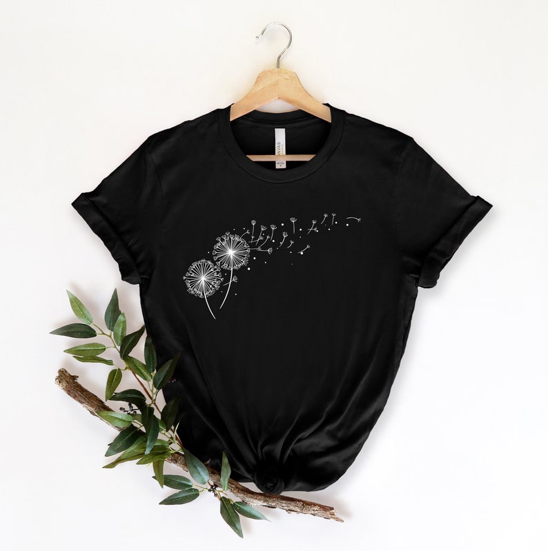 May include: Black t-shirt with a white graphic of two dandelions with seeds blowing in the wind.